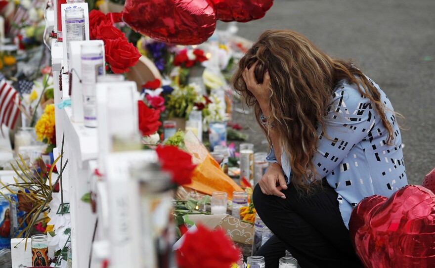 Gloria Garces kneels Tuesday in front of crosses at a makeshift memorial near the scene of a mass shooting at a shopping complex in El Paso, Texas.