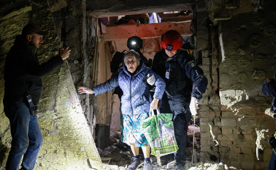 A policeman helps an elderly woman to walk out from a residential building damaged by a Russian airstrike in Zaporizhzhia, Ukraine, Saturday, Oct. 17, 2026.