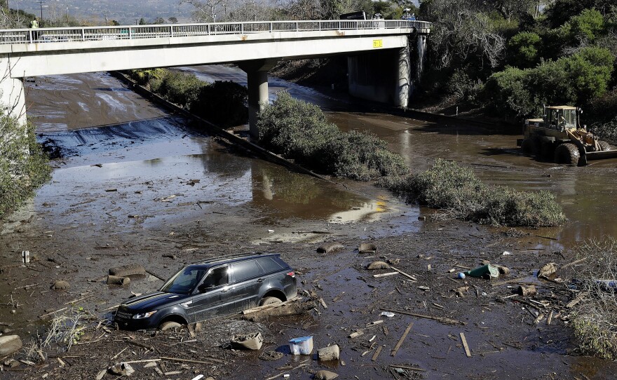 A bulldozer moves debris as a vehicle sits stranded in flooded water on U.S. Highway 101 in Montecito, Calif., Jan. 10, 2018.
