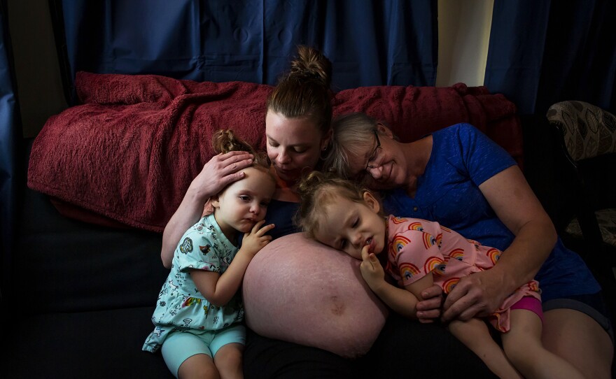 Chelsea Isaacs sits on the couch in her RV with her 2-year-old twin daughters, Harper and Riley, and her mother, Kim Schwartz, on June 11 in Magalia, Calif. They have been living for almost a year in an RV after the Camp Fire destroyed their home in 2018. A month after their house burned down, Chelsea found out she was pregnant with a second set of twins with her partner, Noah.