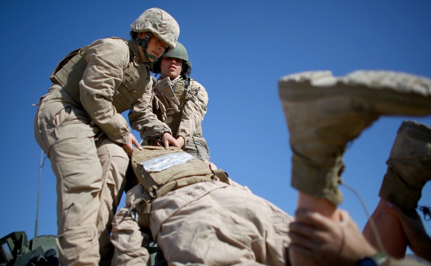 Marine Lance Cpls. Julia Carroll (left) and Paula Pineda lift "Carl" — a 220-pound test dummy — during training in March in California. Female Marines have completed months of training and are now waiting to hear whether they will be allowed to serve in combat roles.