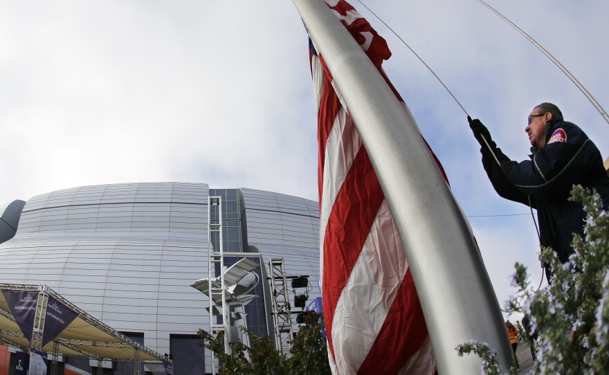 Security worker Ken Trebilco raises an American flag before the big game.