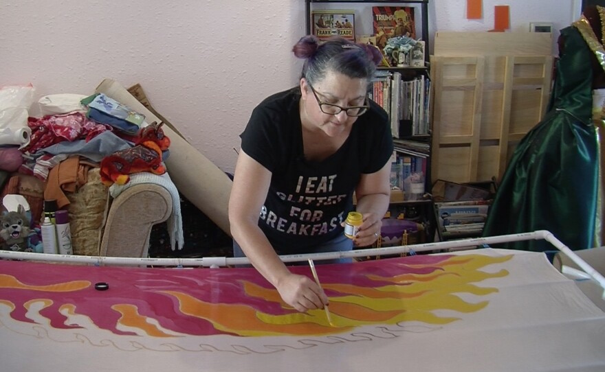 Arabella Benson painting silk wings for her rococo Phoenix costume. The wings had to be scrapped because they were not dry in time.