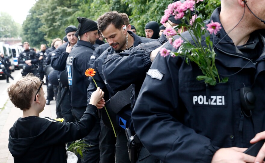 A boy hands flowers to police as they watch a demonstration pass by during G-20 Summit meetings on Saturday.