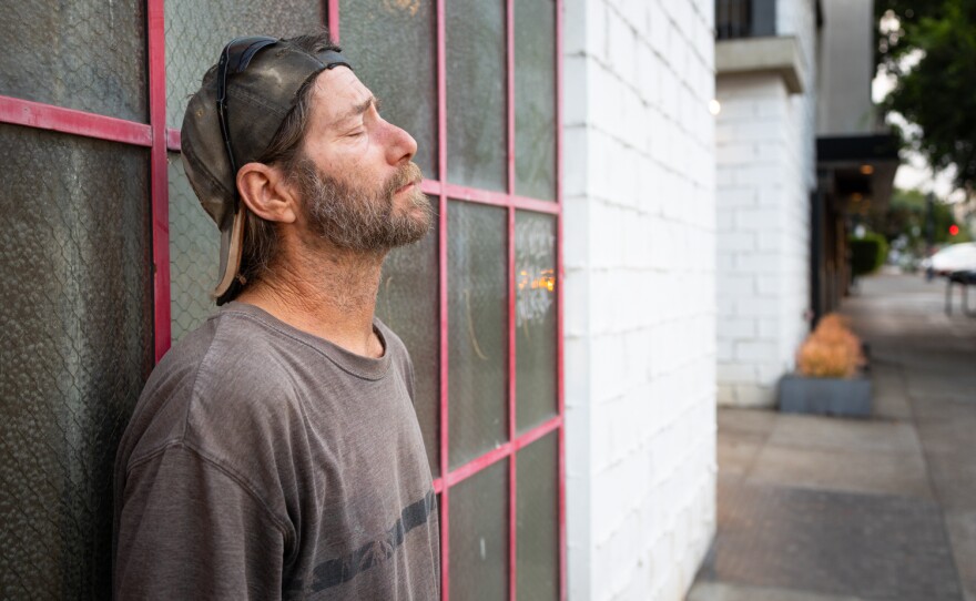 Arley Adcock pauses during a walk with his dog, Cheyenne, in San Diego on June 8.