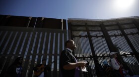 Reverend Guy A. Leemhuis, center, of the Holy Faith Episcopal Church of Los Angeles, leads a song on the U.S. side of the border fence separating Tijuana, Mexico, from San Diego, April 3, 2017. 