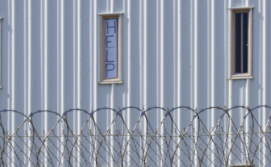 A sign that reads, "HELP," is posted in the window of an inmate cell during a tour with state officials at Holman Correctional Facility in Atmore, Ala., on Oct. 22, 2019. The Justice Department filed a lawsuit this week against Alabama over conditions in its prisons.