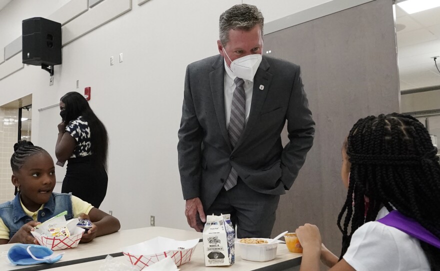 Mike Burke, Palm Beach County superintendent of schools, chats with students as they eat breakfast on Tuesday. The school district has asked 440 students to quarantine just days into the school year.