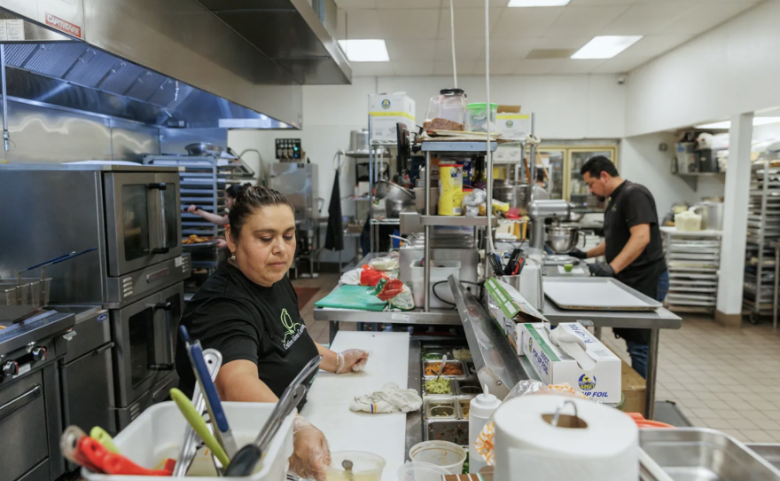 Leticia Andrade, cocinera de línea, a la izquierda, prepara un pedido de almuerzo en Creative Ideas Catering, una pequeña empresa, en San Francisco el 11 de junio de 2024. Foto de Juliana Yamada para CalMatters