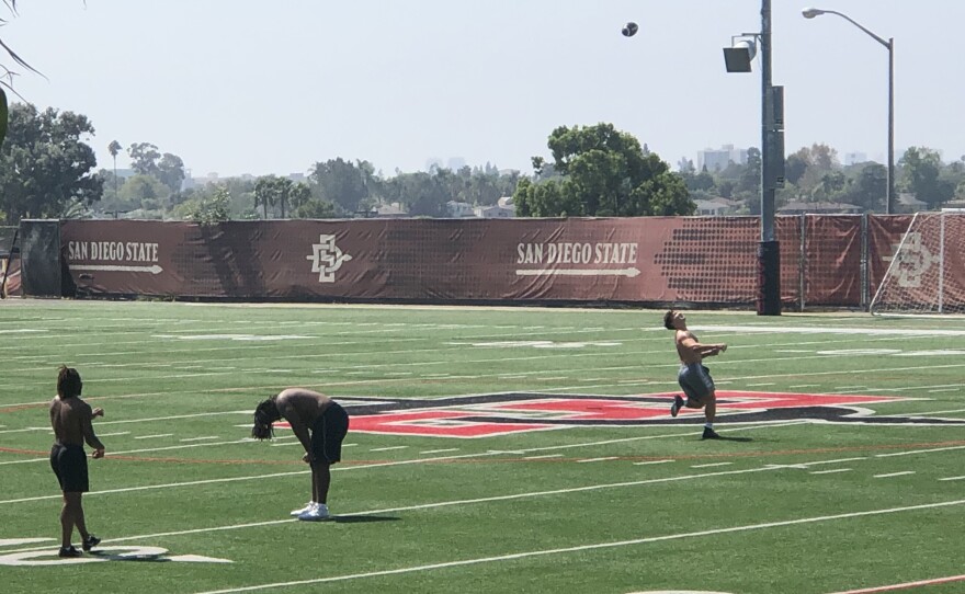 Three SDSU football players practice on a campus football field, Sept. 25, 2020.