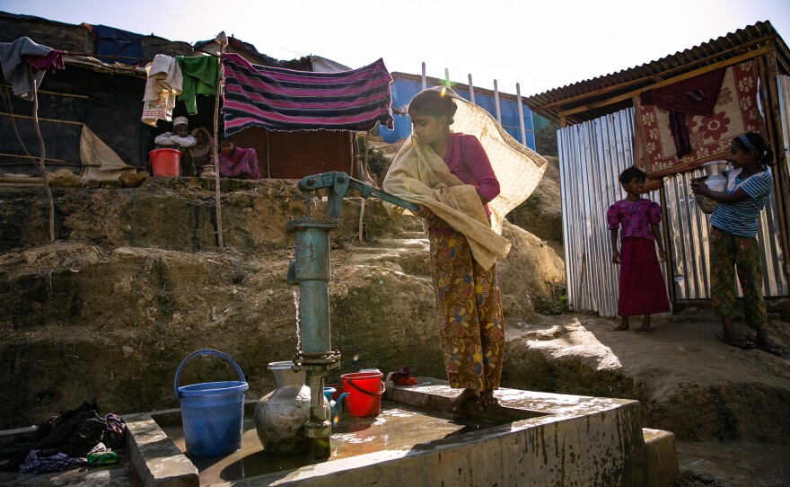 Sanura Begum collects water from a communal pump near her shelter in the Kutupalong Rohingya refugee camp in Bangladesh. Back in Myanmar, she says her family had their own well on their farm.