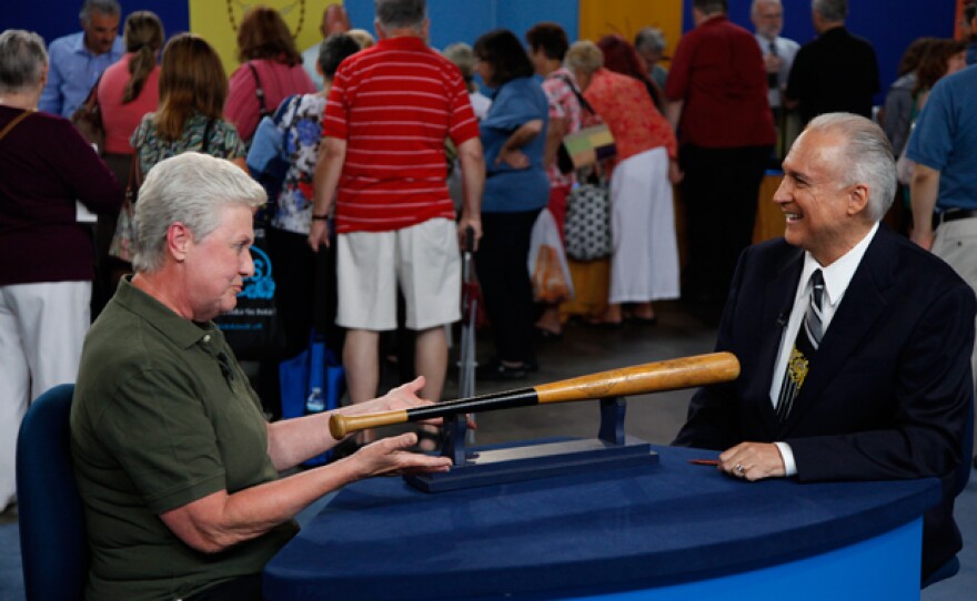 Mike Gutierrez (right) with a guest and a bat used by Mickey Mantle.