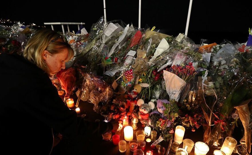 A woman lights a candle on Monday in Nice, France, near a makeshift memorial for the victims of the deadly Bastille Day attack.