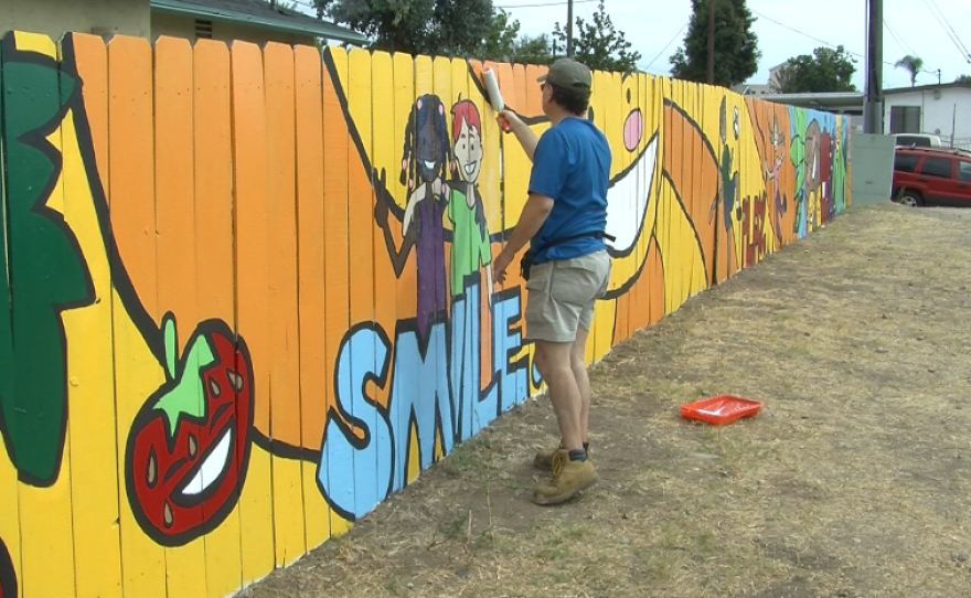 Volunteer Sean Dudley helps protect a new mural by Market Creek Plaza from graffiti.