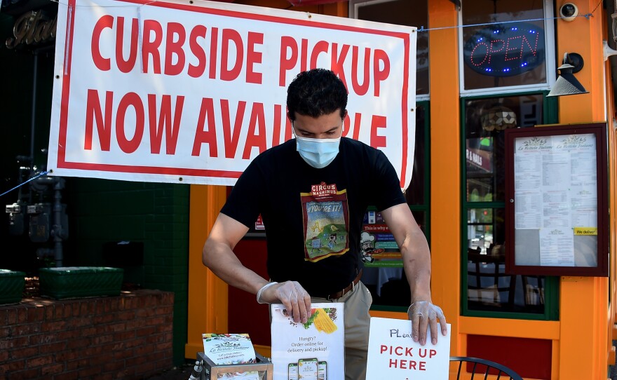 An employee sets a table for pickup orders at a restaurant in Arlington, Va. Even as states are moving to reopen their economies, tens of millions are out of work.