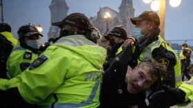 A man is arrested by police in Ottawa on Thursday as demonstrators and supporters gather in a protest against COVID-19 measures that has grown into a broader anti-government protest.