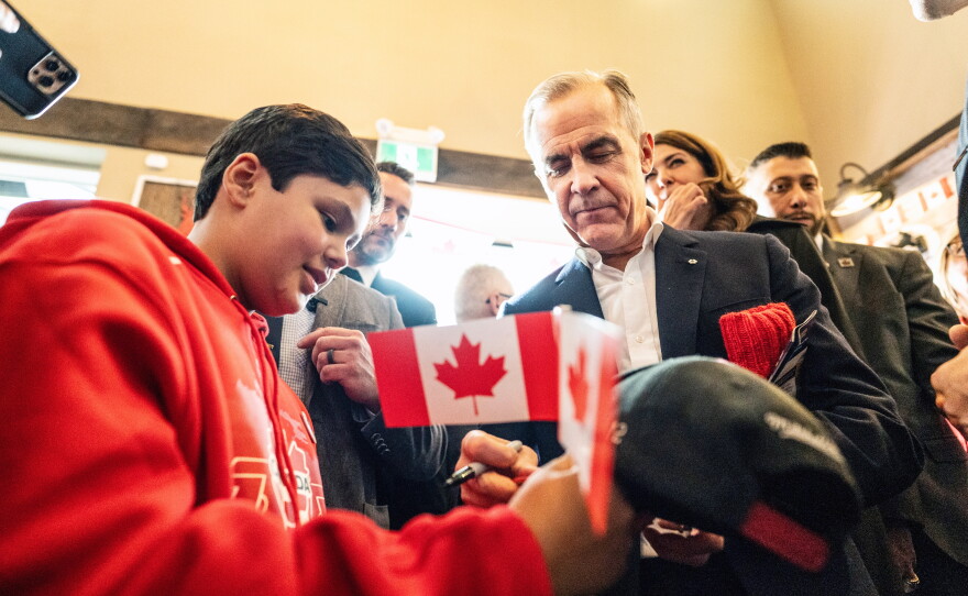 Canada's Prime Minister Mark Carney signs an autograph as he attends a national unity rally in Red Deer, Alberta, Friday Oct. 16, 2026.