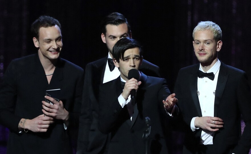 Healy (with microphone) and the other members of The 1975 (from left: George Daniel, Ross MacDonald and Adam Hann) accept the award for British Album of the Year at the 2019 BRIT Awards.