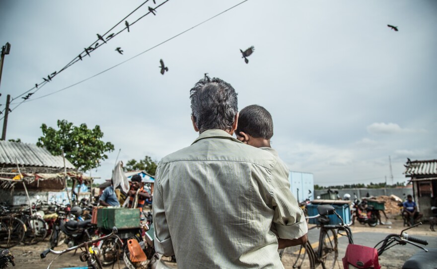 Navaratharasa holds his grandchild at the seaside where he used to bring his child Sathees Kumar, who disappeared in 1996.
