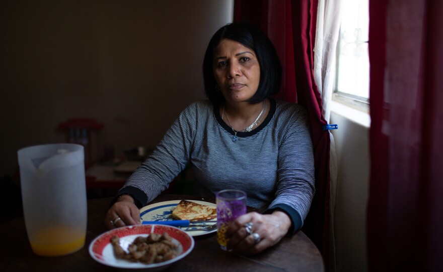 Yroné Camelia Araujo Barreto, a 50-year-old Venezuelan migrant living in Quito, Ecuador. She is eating a traditional Venezuelan dish of <em>cachapa, </em>round dough made from corn, filled with pork. She typically eats two meals a day if she's lucky enough to afford it but says she'll give money or some food to others in need.