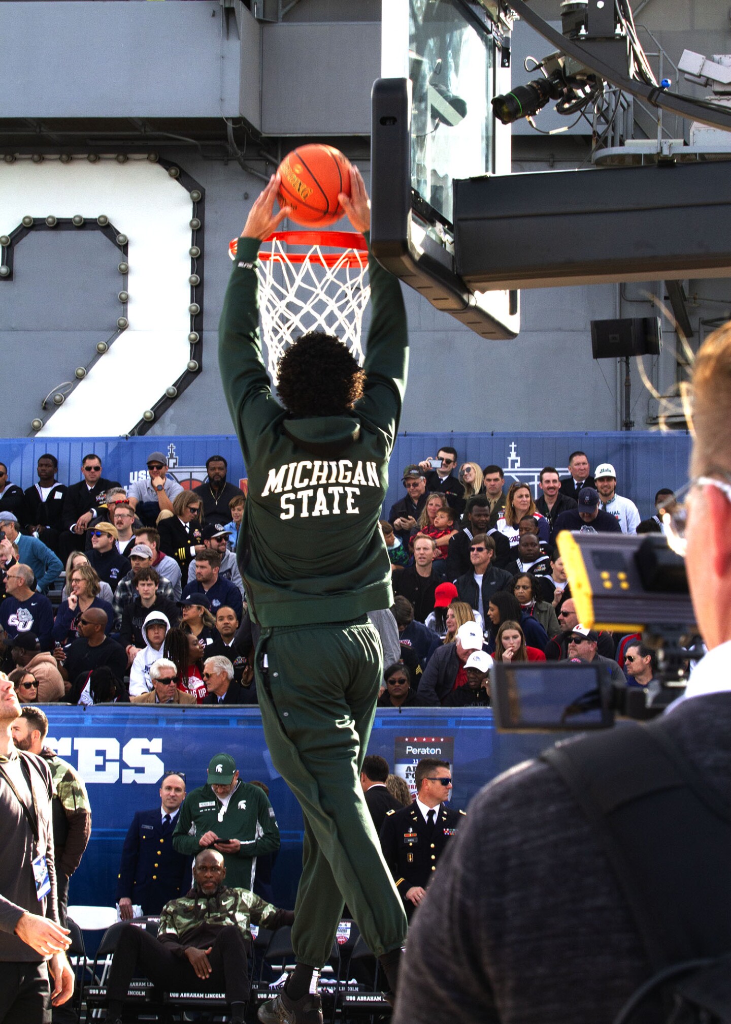 A Michigan State player slam dunks the ball during warm ups before the Armed Forces Classic begins as the sun sets aboard the USS Abraham Lincoln on Nov. 11, 2022.