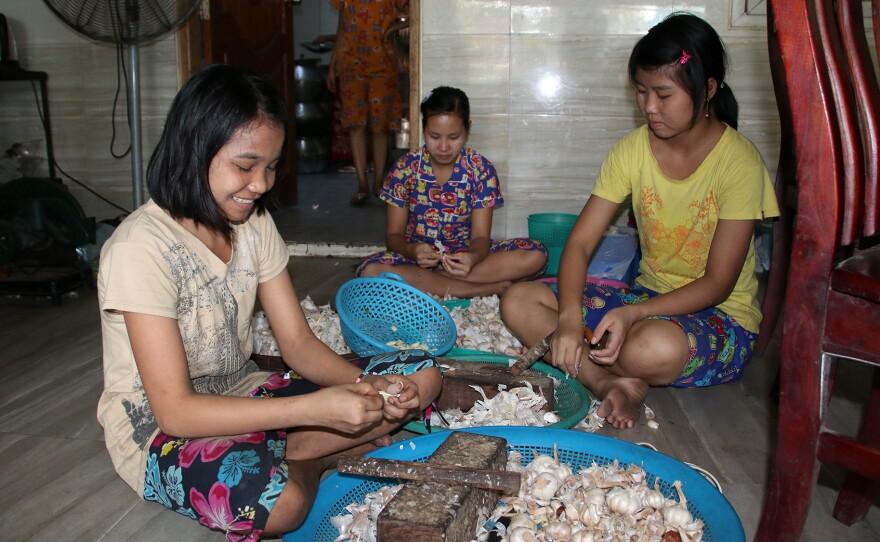 Girls prepare garlic to go in the mohinga at a Myaungmya Daw Cho restaurant in Yangon.