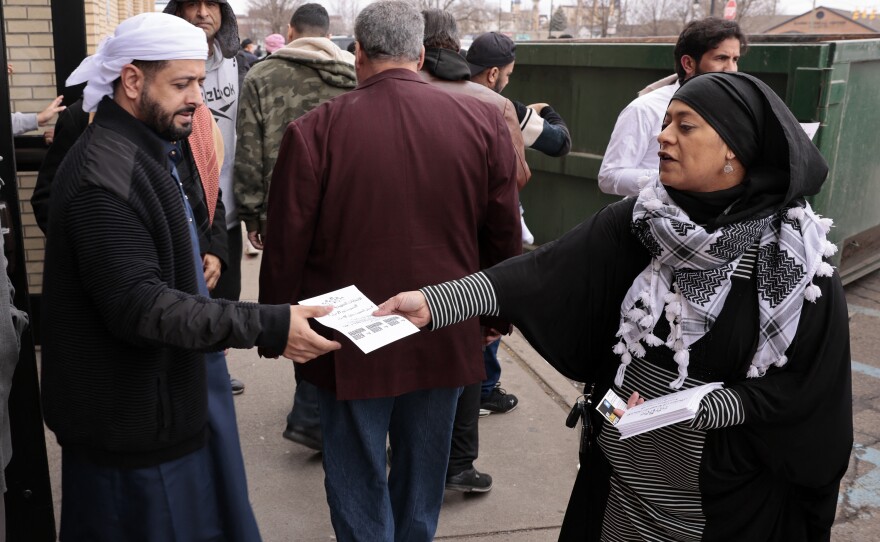 Samraa Luqman (R) hands out fliers outside of the American Moslem Society Mosque to ask voters not to vote for President Biden in Dearborn Heights, Mich., on Feb. 16, 2024.