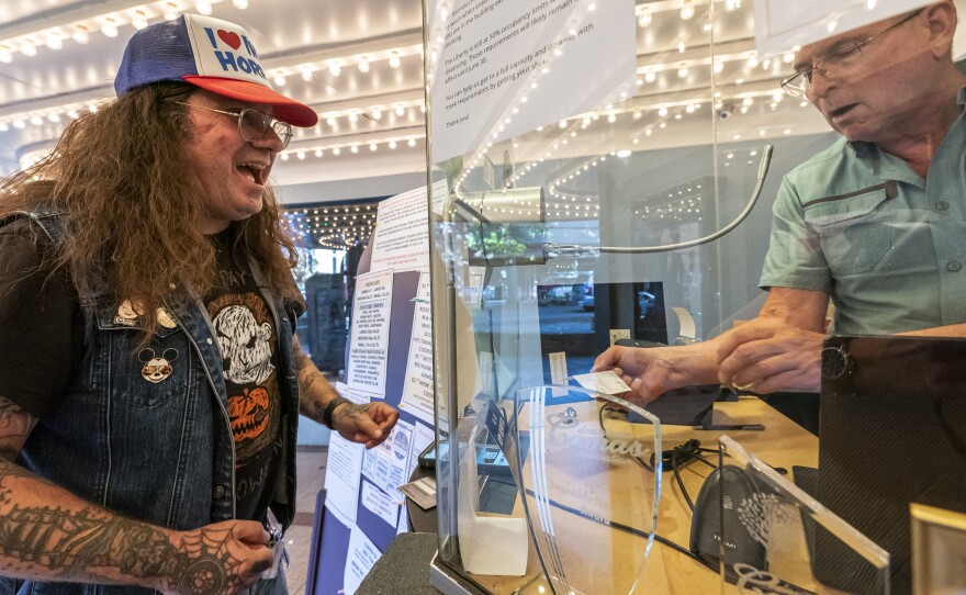 Darren Ford (left) reacts to the new mask guideline while presenting his vaccine card at Liberty Theatre on May 14 in Camas, Wash. Gov. Jay Inslee announced last Thursday that the statewide mask mandate would no longer apply to fully vaccinated adults.