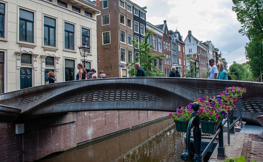 The almost 40-foot 3D-printed pedestrian bridge designed by Joris Laarman and built by Dutch robotics company MX3D has been opened in Amsterdam six years after the project was launched. The bridge, which was fabricated from stainless steel rods by six-axis robotic arms equipped with welding gear, spans the Oudezijds Achterburgwal in Amsterdam's Red Light District.