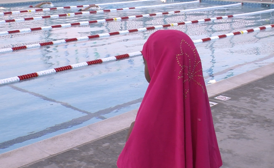 A young girl in a headscarf watches men swim at the Copley-Price Family YMCA Dec. 19, 2015.