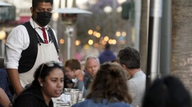 A server tends to customers in an outdoor dining area amid the COVID-19 pandemic on The Promenade Wednesday, June 9, 2021, in Santa Monica, Calif.