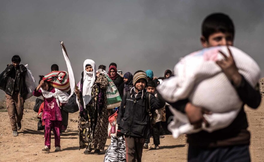 Civilians wave white flags as they flee a west Mosul suburb during heavy fighting between government forces and ISIS militants in February. Many had been warned by ISIS that they would be killed if they tried to escape.