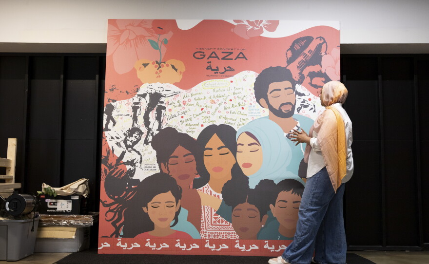 Jannah Sellars, the creative and cultural organizing manager at IMAN, shows a piece of art by Shirien Damra made for a Gaza benefit concert, now displayed in the Arts Lounge in the organization's headquarters.