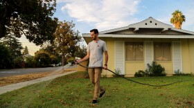 Brandon Miller waters the lawn in front of his Riverside home, July 17, 2018.