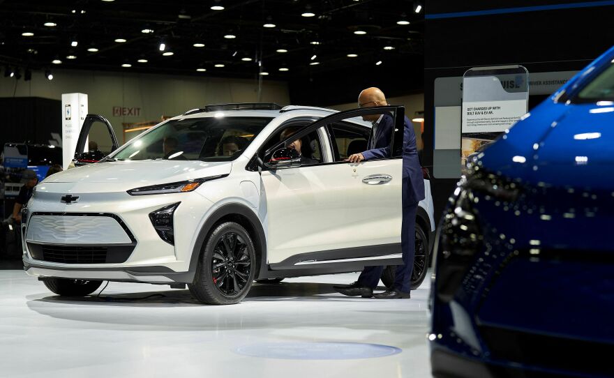 A man looks at a Chevy Bolt EUV at the North American International Auto Show in Detroit on Sept. 14, 2022. It's still unclear whether Chevy Bolts will qualify for the full tax credit or just half of it.