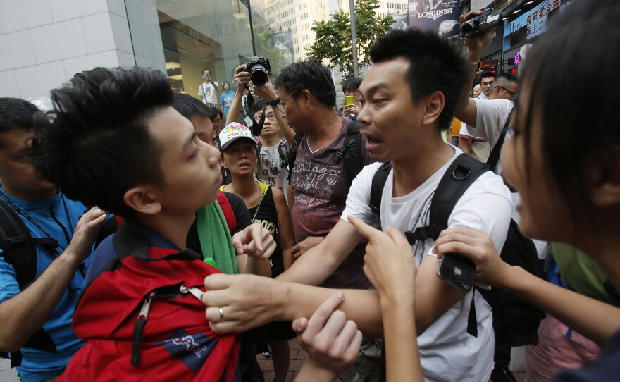 A pro-democracy student protester, left, is pressed by angry locals trying to remove the barricades blocking streets in Causeway Bay, Hong Kong, on Friday.