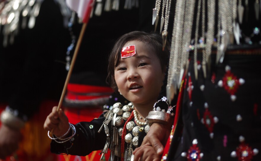 A girl from the Kachin ethnic group waves the flag of Suu Kyi's National League for Democracy as the democracy leader arrives in Namti village last week.