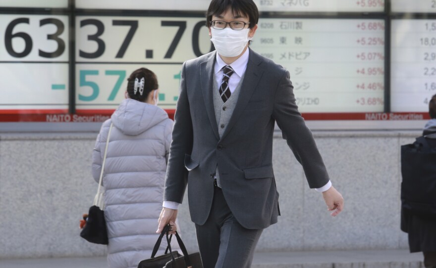 People walk by an electronic stock board of a securities firm in Tokyo on Tuesday. Shares fell sharply in Asia after Russian President Vladimir Putin ordered troops into separatist regions of eastern Ukraine.