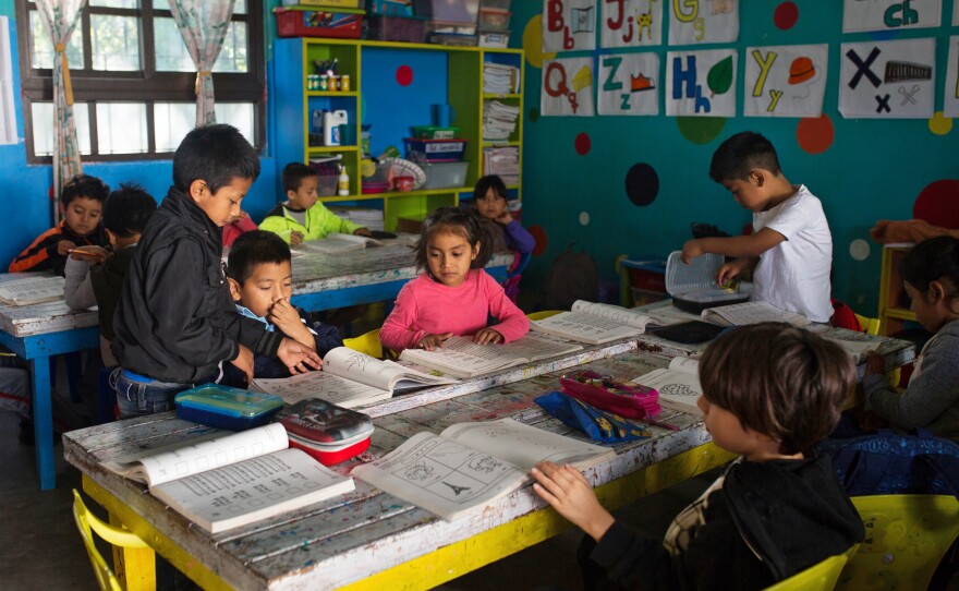 Pre-elementary school children look through workbooks. In Guatemala, where childhood is threatened by poverty, gang violence, drug addiction, and generalized low self-esteem, <em>Los</em> <em>Patojos</em> is seen as a ray of light.