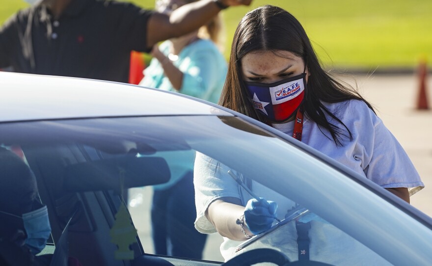 An election worker accepts a mail-in ballot from a voter at a Houston drop-off site on Wednesday. A federal judge blocked Gov. Greg Abbott's order limiting one drop-off site per county late Friday.