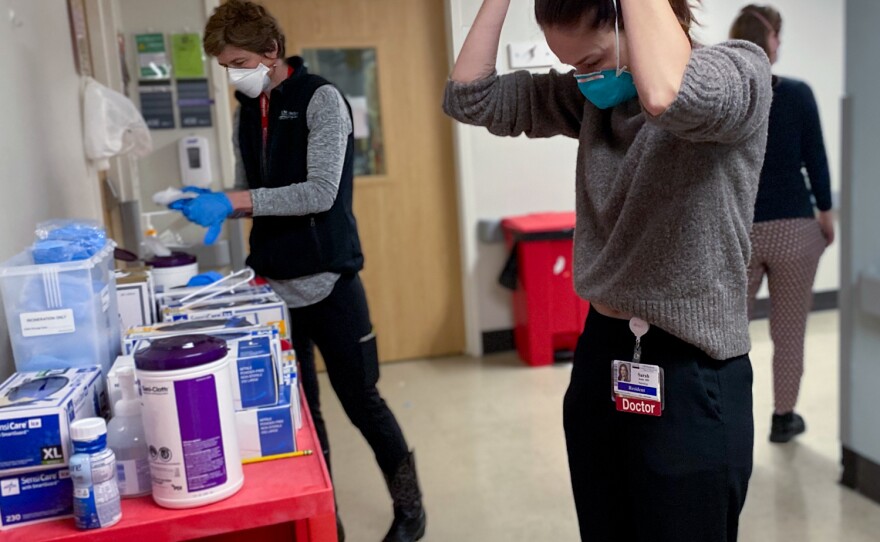 A resident at Harborview Medical Center in Seattle puts on a mask before entering a patient's room on January 14, 2022.