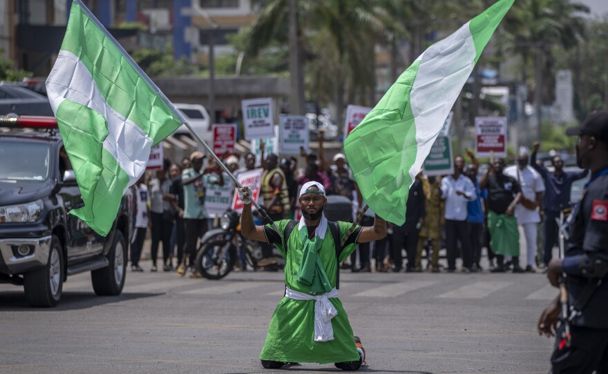 A demonstrator holds two Nigerian flags as he and others accusing the election commission of irregularities and disenfranchising voters make a protest in downtown Abuja, Nigeria.