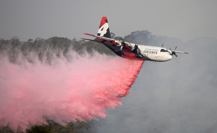 A New South Wales Rural Fire Service large air tanker drops fire retardant on the Morton Fire burning in bushland close to homes at Penrose, south of Sydney, on Friday.