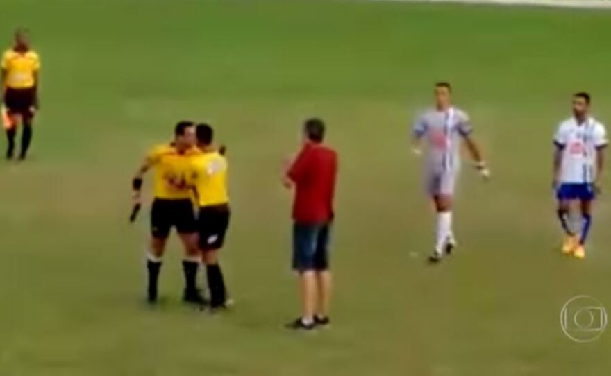 A referee is restrained at an amateur game in Brazil after running onto the field brandishing a pistol.