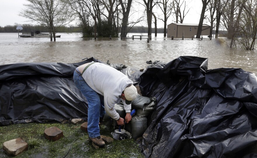 In Clarksville, Mo., Bob Bailey adjusts a pump as he tries to keep floodwater from the Mississippi River out of a rental property Sunday. The small community has worked for days to build a makeshift sandbag levee.