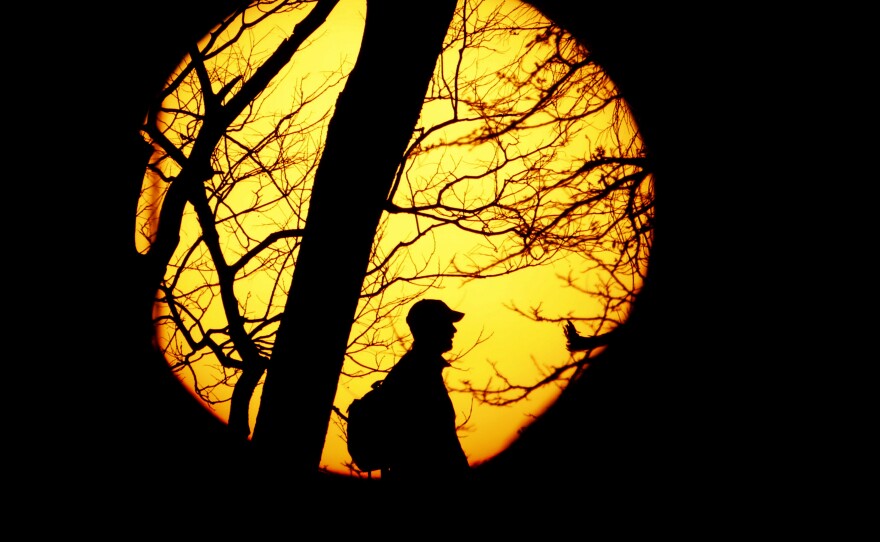 A man is silhouetted against the sun on a bluff overlooking downtown Kansas City, Mo., Wednesday.