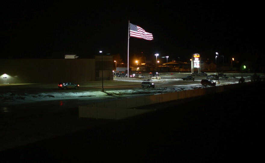 The American flag waves above the parking lot of the brand new strip mall in Sidney.