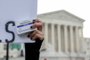 An abortion-rights activist holds a box of mifepristone pills as demonstrators from both anti-abortion and abortion-rights groups rally outside the Supreme Court on March 26, 2024.