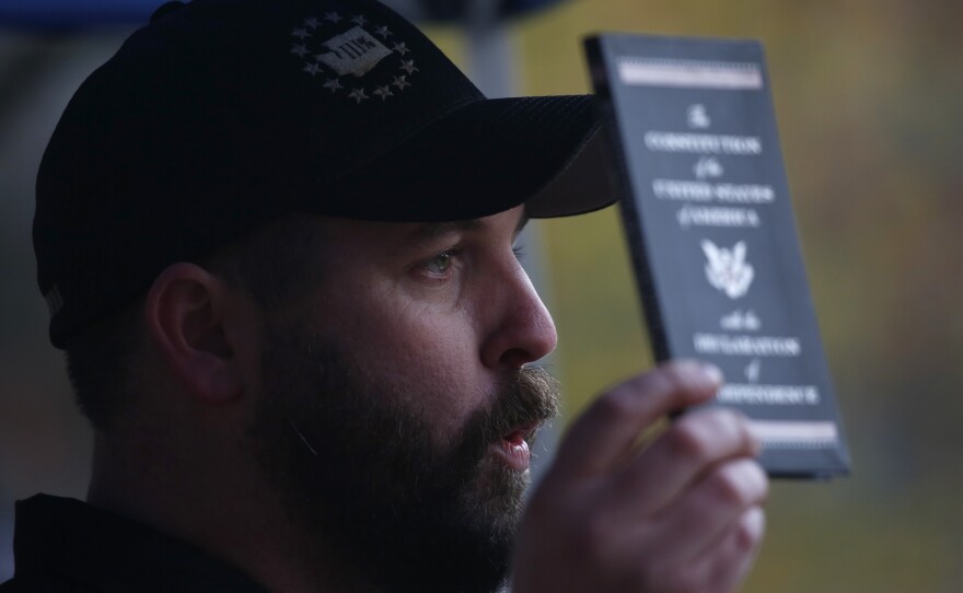 Matt Marshall, state leader of the Washington Three Percent, holds a copy of the U.S. Constitution during the United Against Hate rally.