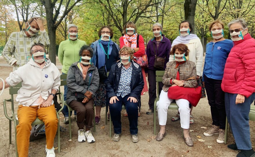 Suzy Margueron (seated, center) who advocates for people with hearing loss, likes to gather with friends in Paris' Luxembourg Gardens. All have transparent masks, but say it's others who should be wearing them too.